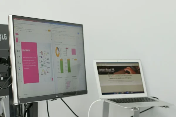 External monitor and laptop showing analytics dashboards on a tidy desk.
